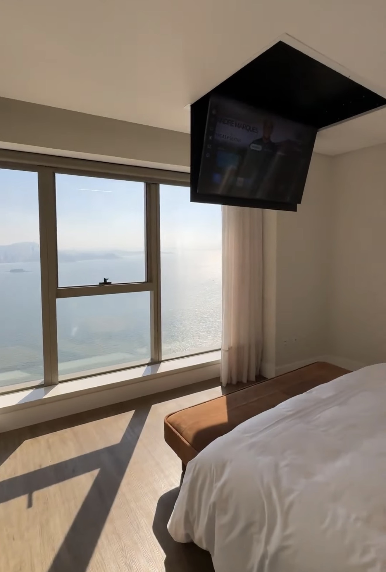 Suíte master do Yacht House com TV de teto retrátil (sistema Flap) aberta e vista para o mar de Balneário Camboriú